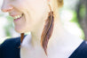 Woman wearing leather feather earrings.