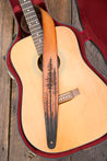 Acoustic guitar in case with leather lodgepole pine forest guitar strap