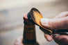 Close up detail of forest bottle opener key fob cracking open a bottle of beer