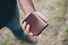 Man holding folded four pocket leather wallet in rich brown 