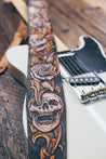 Close up detail of hand-carved skull and scrollwork on leather guitar strap