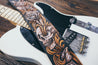 Close up detail of hand-carved skull and scrollwork on leather guitar strap