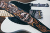 Leather guitar strap lying on electric guitar. Close up detail of hand-carved skull and scrollwork 