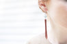Model wearing handcrafted leather fringe earrings with aquamarine gemstone round