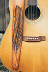 Details of hand carved and tooled feather on leather guitar strap, shown in natural