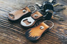 Side view of mountain and forest bottle opener key fobs with keys attached