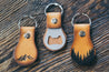 Hand-crafted leather key fobs with stainless steel bottle opener. Shown in two designs: mountains and forest