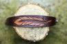 Detail of hand carved feather on leather cuff bracelet