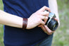 Model holding a camera wears the leather Engraver's Scroll Cuff Bracelet
