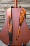 Hand carved lodgepole pine forest leather guitar strap shown on guitar