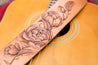 Close up detail shot of hand-carved peony flower design on leather guitar strap