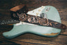 Close up of leather skull and roses guitar strap resting on electric guitar