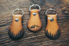 Hand-crafted forest and mountain leather key fobs on wood background