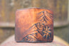 Handcrafted leather wallet with tooled design featuring a topographical mountain range and compass rose