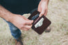 Man easily pulls debit card from exterior pocket of leather wallet