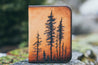 Handcrafted leather wallet with tooled design featuring a forest of lodgepole pine trees