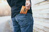 Man placing handcrafted lodgepole pine tree leather wallet into the back pocket of his jeans