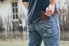 Man putting Four Pocket leather wallet into the back pocket of his jeans