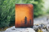 Handcrafted leather wallet with tooled design featuring a small forest of lodgepole pine trees
