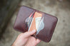 Interior of six pocket wallet handcrafted with Mahogany leather. Wallet filled with credit and debit cards and cash